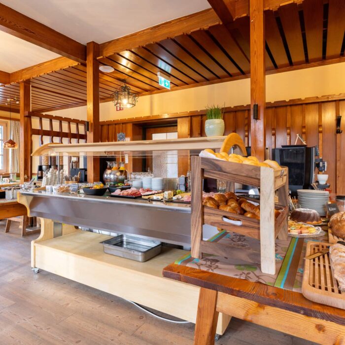 Buffetbereich in einem Restaurant mit Holzinterieur, vielfältiger Auswahl an Speisen und Backwaren auf einem Serviertisch, ideal für Frühstück oder Brunch.