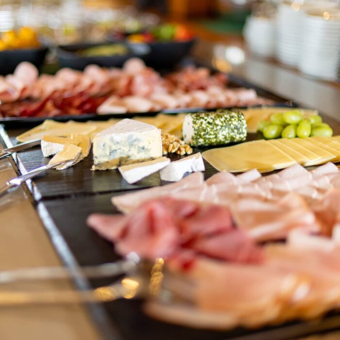 Bunte Auswahl an Wurst- und Käseplatten auf einem Buffet, dekoriert mit Trauben und anderen Beilagen, ideal für Feiern und Veranstaltungen.
