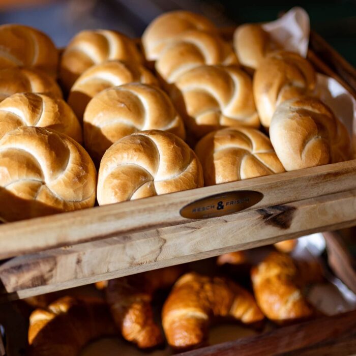 Korb mit frisch gebackenem Gebäck, darunter goldbraune Brötchen und Croissants, ideal für ein Frühstück oder eine Bäckerei.