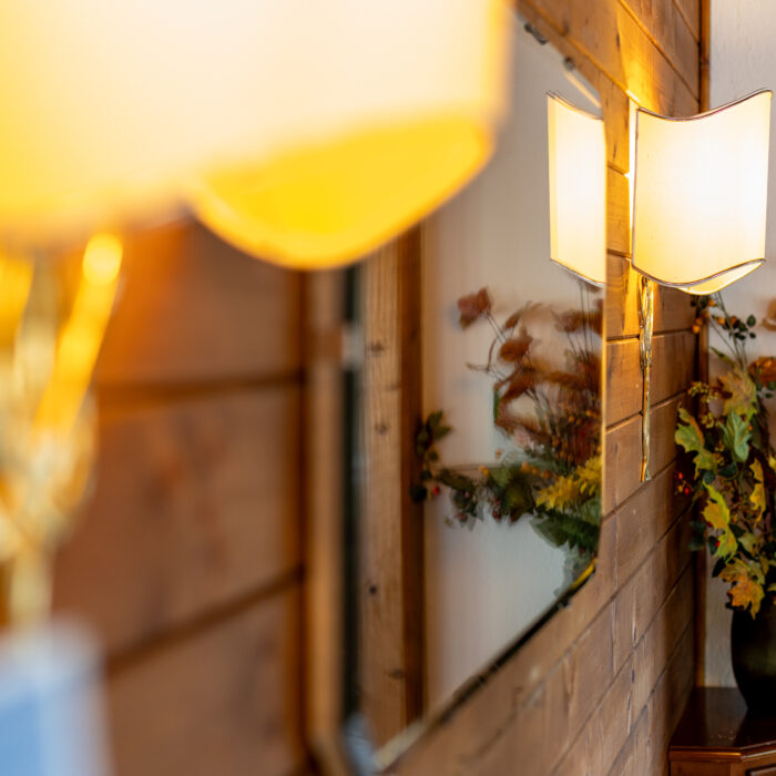Beleuchtete Wandlampe neben Blumenvase