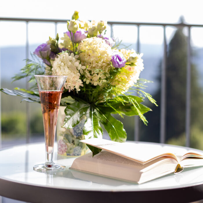Blumenstrauß, Sektglas und offenes Buch