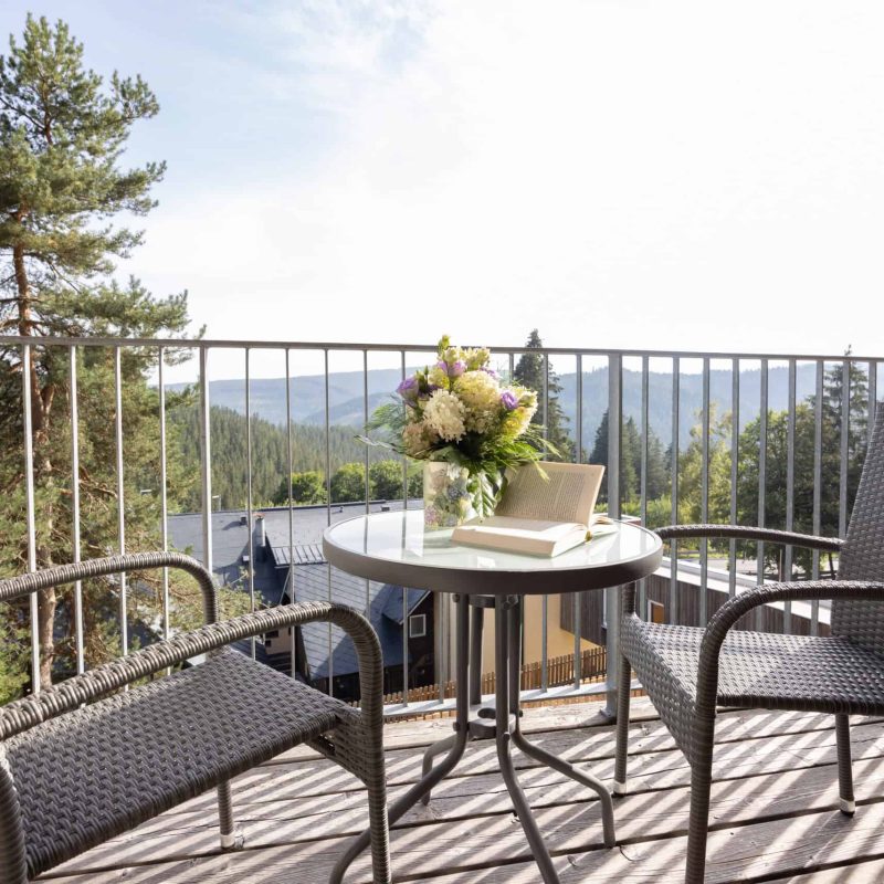 Terrasse mit Bergblick, Sitzmöbeln und Blumenstrauß